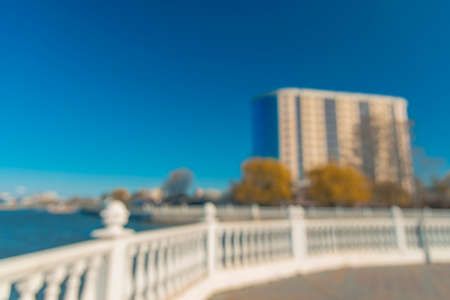 unfocused abstract modern green city idyllic river waterfront district with white fence and building frame silhouette in vivid colorful summer day timeの写真素材