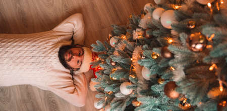 father bearded man middle adult age portrait lay on floor near Christmas tree smiling and looking at camera, festive decorated wallpaper poster winter holidaysの写真素材