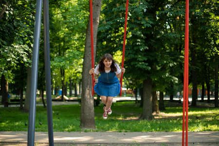 beautiful attractive cheerful teenager girl on swing carousel active entertainment summer time park outside female portrait and happy emotions conceptの写真素材