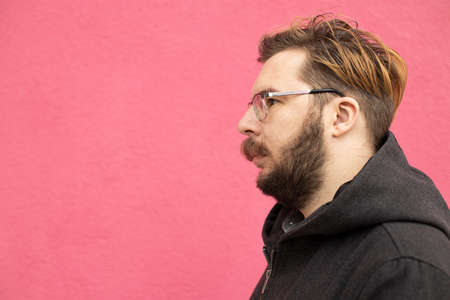 bearded man calm face profile portrait with glasses on pink painted wall concrete background simple pattern space for your text hereの写真素材