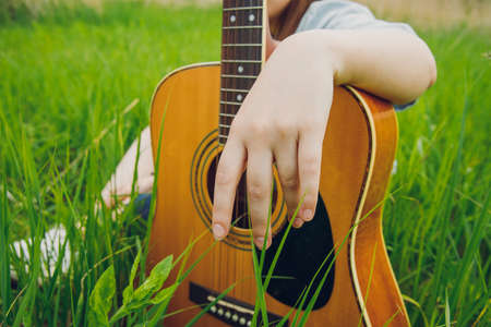 acoustic guitar female hand country music outdoor art concept photography in garden space with green...