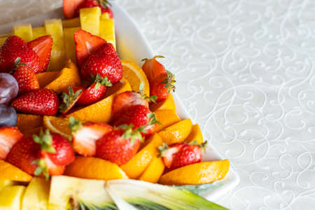 fresh raw fruit plate strawberry orange and pineapple on a white table cloth background texture surface advertising food concept picture with empty copy space for your text hereの写真素材