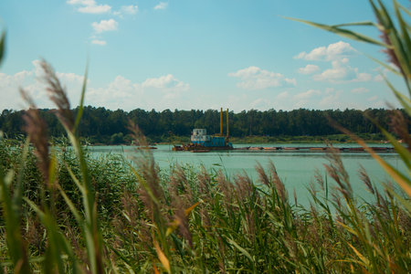 barge industrial object on lake surrounded by peaceful nature environment space in summer day timeの写真素材