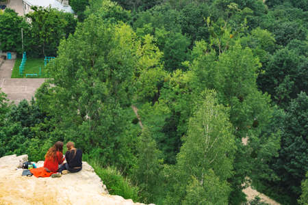 rustic meeting of two girl on edge of small rock with view on green trees park outdoor environment...