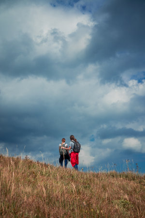 highland dramatic mountain sky vertical picture wallpaper poster photography with hiking couple back to camera active life style concept with empty copy space for your text hereの写真素材