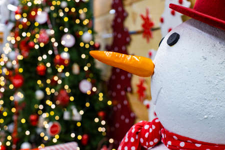 Christmas picture with snow man foreground space and decorated tree with garland illumination lighting bokeh unfocused effect, winter holidays eve timeの写真素材