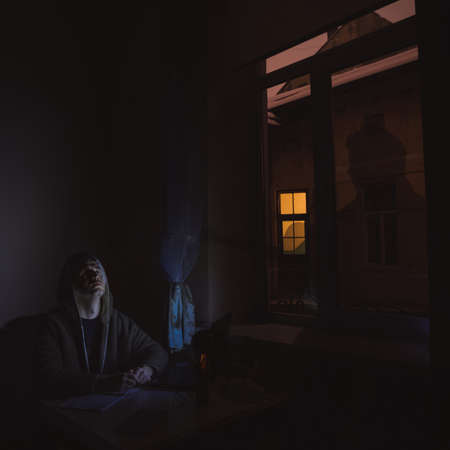 isolation and night working of middle age person programmer with laptop at home, night time artistic foreshortening with view view and yellow light in dark, empty copy space for your textの写真素材