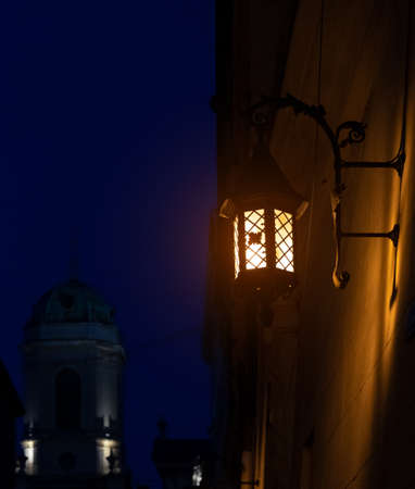 fairy tale medieval town landmark view with lamp post yellow beautiful lighting in Christmas time with Christian church silhouette background at phantom darknessの写真素材