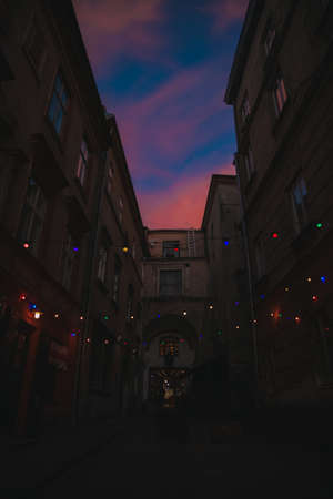 old city passage with festive garland lights multi colored urban environment street space vertical photography in evening dusk timeの写真素材