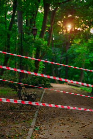 forbidden striped ban tape fenced park territory foot path trail in walking zone for quarantine...
