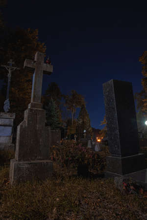 cemetery beautiful night scenic view with tombstones and graves at darkness time with phantom blue sky color and street lamps illumination, vertical photography and Halloween thematicの写真素材
