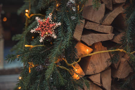 Christmas rural cozy decorations of star, needle branches, garland lights and firewood, soft focus on red toy, December winter holidays festive timeの写真素材