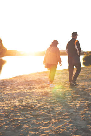 morning sun light above beach with walking couple of people silhouette back to camera, vertical photography with unfocused conceptの写真素材
