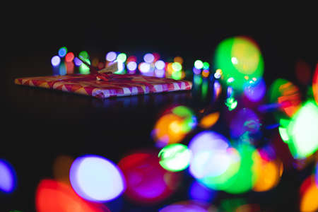 dark unfocused style photography of gift on holidays Christmas small box with ribbon on table, with...