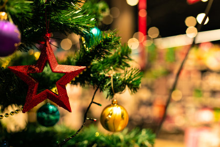 Shopping mall traditional decoration of Christmas spruce tree with sparkle red star toy on branch and blurry festive backgroundの写真素材