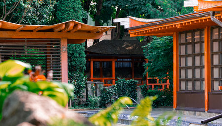 Japanese style restaurant yard garden landscaped design in sunny day time with foreground bush and background red buildingの写真素材