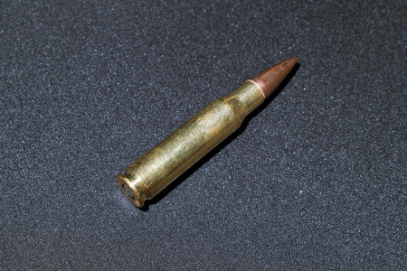bullet bronze rifle ammunition armed single object gray neutral textured floor surface perspective