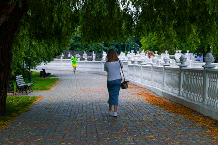 city landmark autumn walking side street cobble stone area in September morning time in park with walking woman back to cameraの写真素材