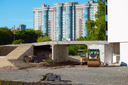 development building construction area with cement materials gravel and panels with special vehicle road rink and tractor near unfinished house complex for people living in down town district spaceの写真素材