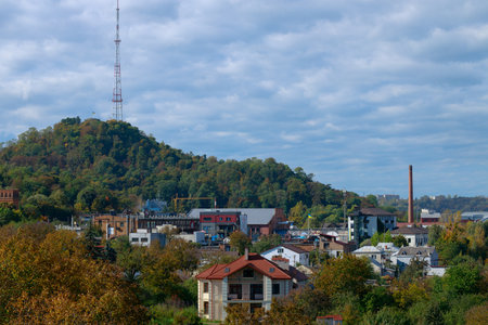 suburban city scape outskirts land cottage living buildings around green hill with tv tower infrastructure object village environmentの写真素材