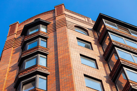 red brick facade loft architecture modern building exterior city scape view foreshortening from below with perspective lines and blue sky spaceの写真素材