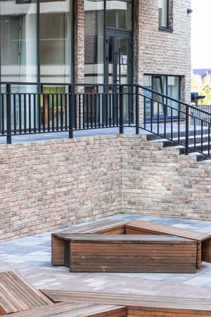 narrow walking side street pavement tile designed bench brick wall aesthetic urban environment with glass windows background building facade viewの写真素材