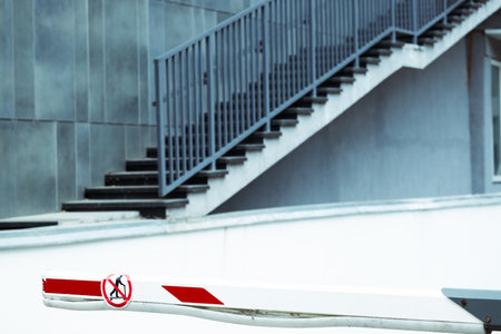urban car parking street space renting place with red white barrier stick and gray wall stairway...