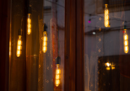 warm light hanging lamps decorative illumination garland windows fuzzy reflection dusk backgroundの写真素材