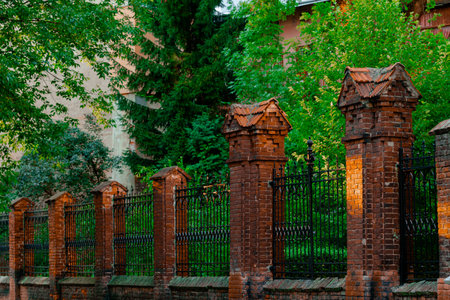 old street alley brick pillar fence around some green ordinary garden spaceの写真素材