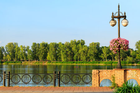 waterfront landscaped district horizontal scenic view along river water with green park picturesque background at clear weather day timeの写真素材