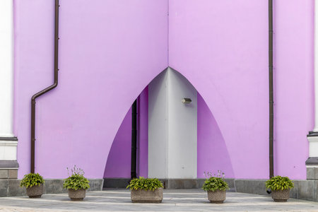 tender pink color facade exterior urban square with triangle arch facade and bush flower pot landscaped building space backgroundの写真素材