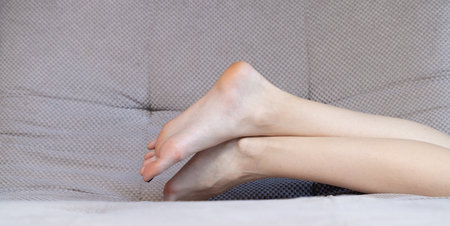 crossed legs white skin European person female body part on couch indoor room with empty space backgroundの写真素材