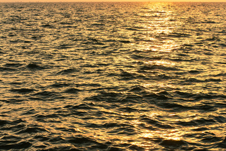 sunset dusk twilight evening lighting wavy waters sea background narrow focus perspective surfaceの写真素材