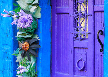 purple door blue walls cottage core aesthetic spring vibes porch side of buildings with decorative flowersの写真素材