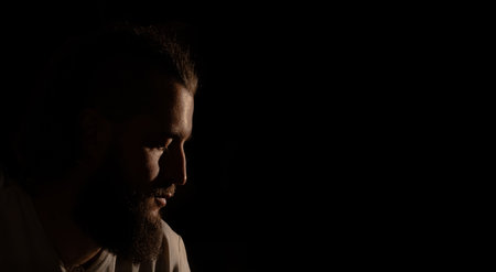 attractive dramatic middle adult age man portrait profile face with Greek nose and facial hair beard black background low key lighting copy spaceの写真素材