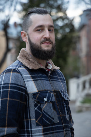 bearded millennial middle adult man portrait calm facial expression vertical photography outdoor...