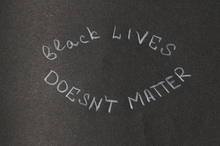 A message of protest and social justice written in chalk on a dark, textured background, conveying a powerful statementの写真素材