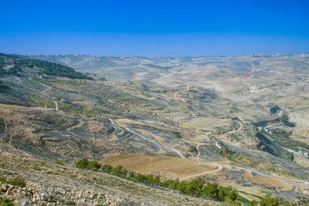 Expansive arid landscape with winding roads and scattered settlements under a clear blue skyの写真素材