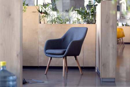 A stylish upholstered chair sits in a bright, modern office environment featuring natural wood...
