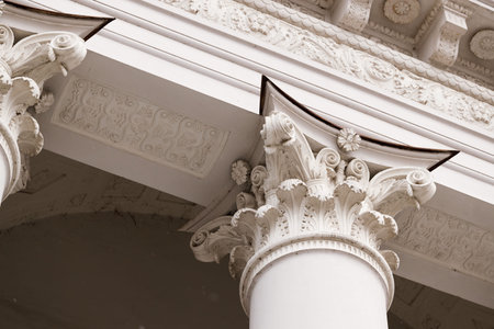 Close-up view of a white Corinthian column capital showcasing detailed acanthus leaves, volutes, and...
