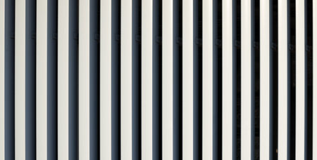 A close-up view of a building facade with repeating vertical elements in contrasting colors, showcasing a contemporary design aestheticの写真素材