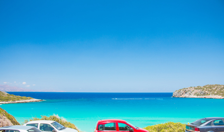Blue and turquoise beachfront with car parking. Voulisma beach near to Agios Nikolaos. Colorful beach with white sand and rocks. Tropical turquoise beach with blue sky. Summer 2018のeditorial素材