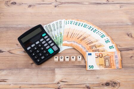 Wooden cubes, calculator and euro money on wooden background. Copy space for text. Euro banknotes....