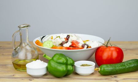 Ingredients for Greek Salad on wooden background. Greek salad with Vegetables on wooden background. Healthy food, Mediterranean diet. Salad ingredients, tomatoes, feta, cucumber, onion, olive oil.の写真素材