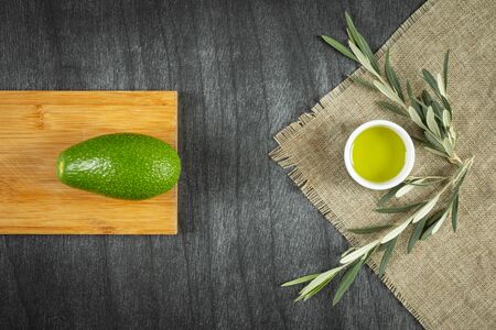 Healthy food concept. Fresh organic avocado, virgin olive oil and olive branches. Avocado with leafs...