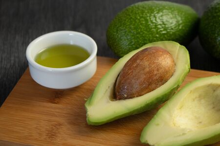 Fresh sliced avocado and olive oil on wooden background. Cosmetic oils, body and face care. Avocado...