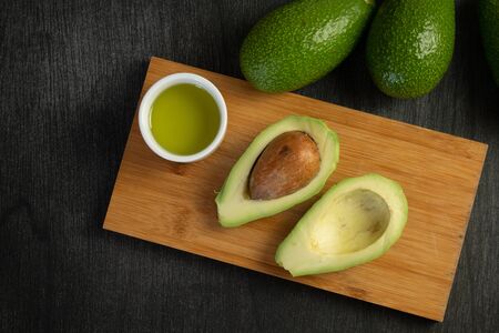 Fresh sliced avocado and olive oil on wooden background. Cosmetic oils, body and face care. Avocado...