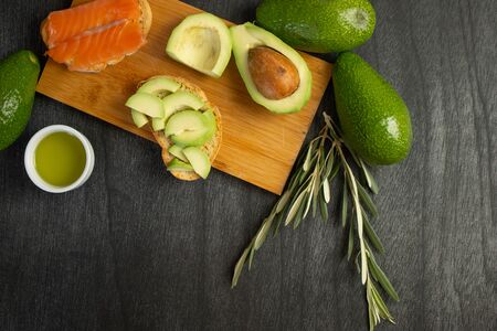Bread with slices avocado. Fresh salmon and avocado sandwich. Healthy food concept. Olive oil and olive branch. Copy space for text.の写真素材