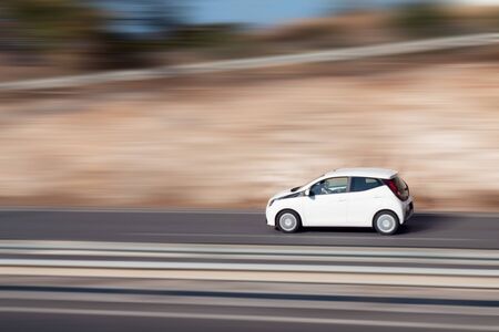 White car moving fast along the street on a motion blurred background. Car driving on freeway,...