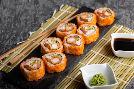 Set of fresh tasty california sushi rolls on a dark background. Wasabi with soy and chopsticks.の写真素材